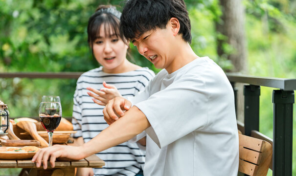 A couple is having trouble with insect bites while eating outdoors.