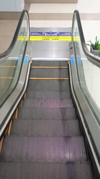 Moving empty escalator steps descending down inside modern public building facility
