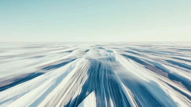 Vast frozen tundra landscape under a clear pale blue sky during the depth of winter with snow drifts and shadows