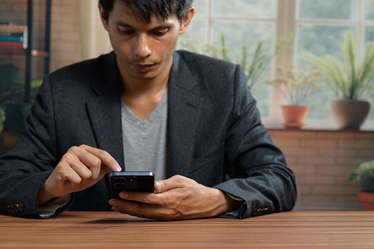 Young Man Using Smartphone at Table in Bright Modern Indoor Setting