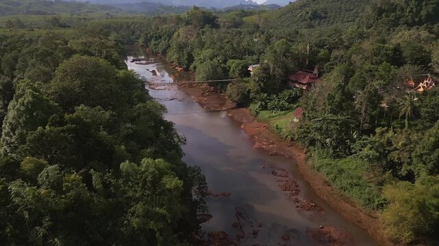 Khlong Phrasaeng red river bed and long suspension rope bridge aerial panning view near Khao Sok National Park in Surat Thani Province, Thailand