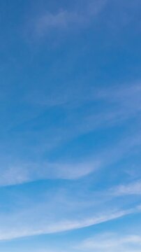 Peaceful daytime sky time-lapse with soft white clouds flowing in a deep blue atmosphere.