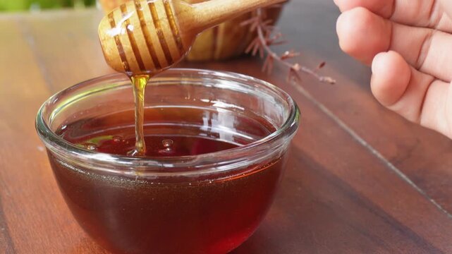 Honey dripping in the glass jar from honey dipper 