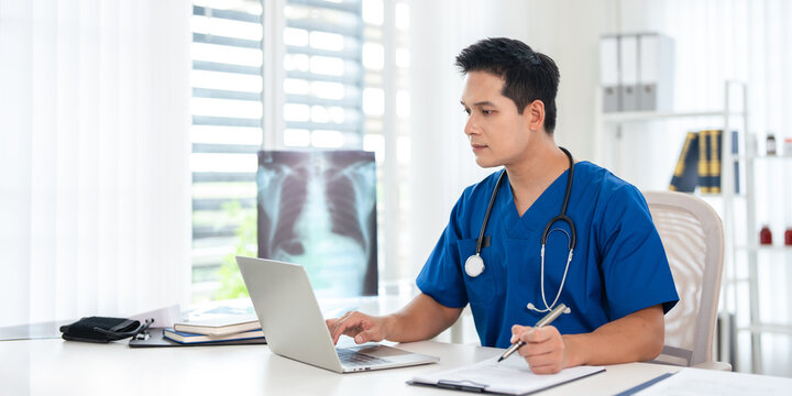 Doctor looking at laptop screen writing in notebook for research planning or medical tech innovation in hospital office. Healthcare medic worker, research strategy book notes and online communication.