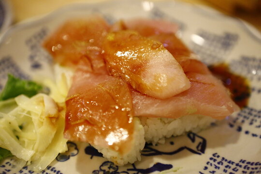 Fresh raw fish nigiri sushi is served on a ceramic plate.
