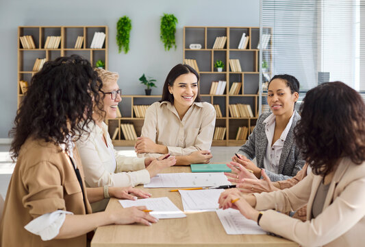 Women team meeting and discussion in office. Colleagues show collaboration at a desk, share ideas, plan strategy and build trust in a bright workspace. Teamwork concept for business success.