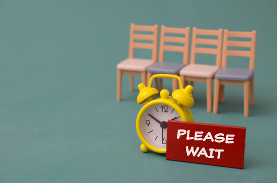 Yellow alarm clock with please wait sign in front of empty chairs for waiting room concept