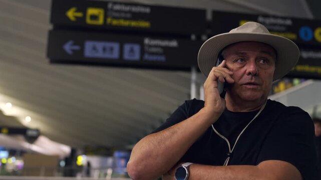 Mature male tourist talking on smartphone in airport terminal