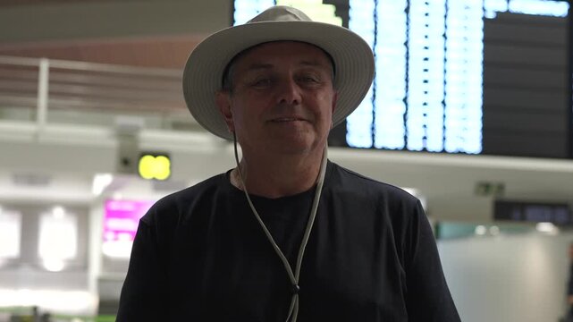 Mature male tourist smiling in airport terminal