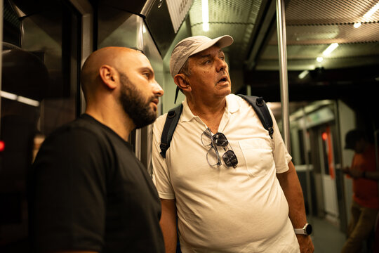 Two men commuting in crowded subway car