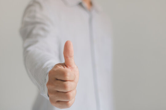 Confident person giving a thumbs up gesture in a white shirt, symbolizing approval, success, positivity, agreement, satisfaction, and support with clean copy space for business and marketing concepts.