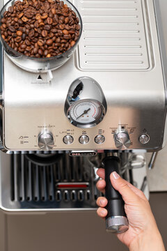 Person Operating Stainless Steel Espresso Machine at Home