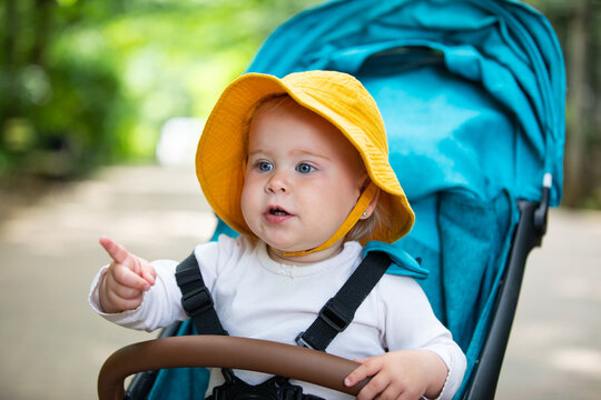 Curious Baby Pointing While Sitting in a Stroller Outdoors