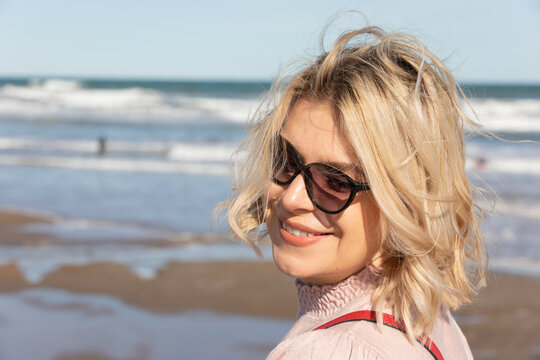 Smiling Blonde Woman Wearing Sunglasses at the Beach