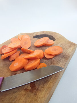 Fresh orange carrot slices and kitchen knife on wooden cutting board