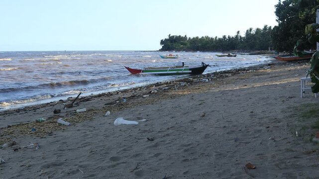 Small waves move slowly on the beach, fishing boats on the shore
