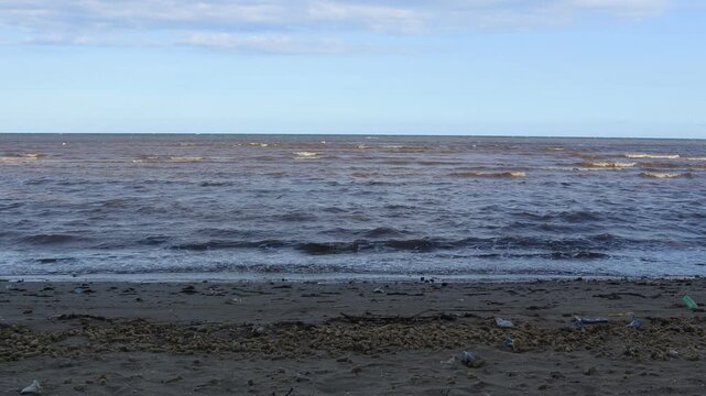 Small waves move slowly on the beach, fishing boats on the shore