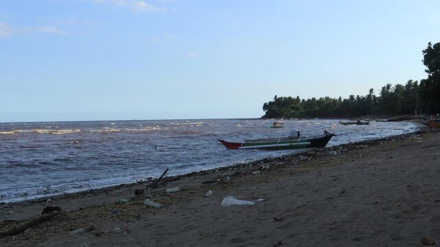 Small waves move slowly on the beach, fishing boats on the shore