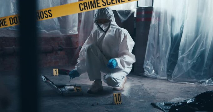 Forensic specialist places a measuring ruler and markers beside evidence on the floor during a crime scene examination.