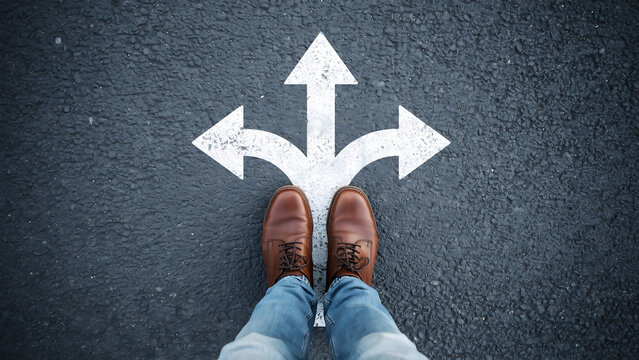 Person standing at a three way road intersection with painted arrows intersection direction decision navigation pavement lifestyle