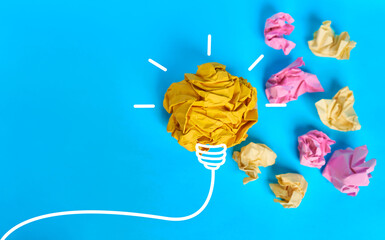 Crumpled yellow paper light bulb with colorful paper balls on bright blue background  © kaliel