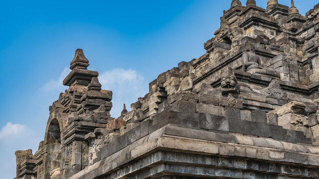 Ancient Hindu architecture. Details. The wall of a stone temple with statues of Buddha, reliefs of Kala Makara. Close-up.  The background is a blue sky. Indonesia. Java. Candi Borobudur