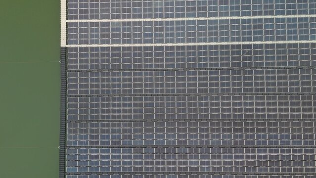 Aerial drone view of floating solar cell panel farm on water reservoir for renewable clean energy generation. Sustainable green power plant and ecology technology concept.