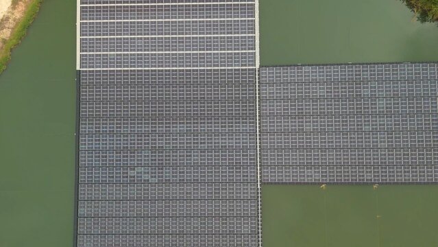Drone aerial perspective of floating photovoltaic solar panels on lake or pond for clean electricity supply. Environmental friendly green energy and modern infrastructure.