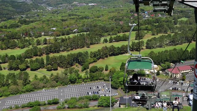 Horizontal travel footage from Mount Omuro funicular in Japan, featuring panoramic view of green hills, cableway and sunny coastal scenery. Ideal for tourism, nature and adventure themes.