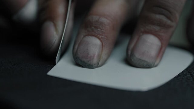 Close up of skilled hands cutting leather with a knife for shoe production indoors