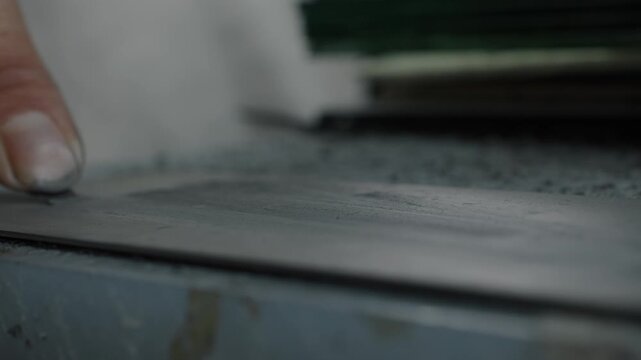 Close-up of hand cutting material with blade on workbench in shoe production process