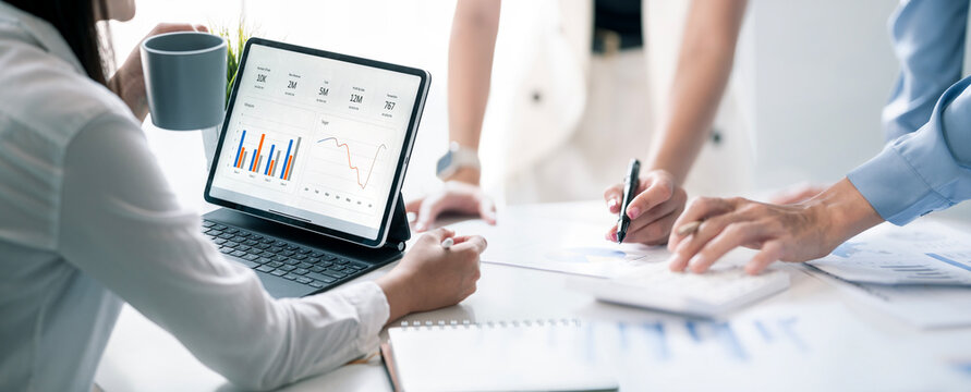 Business team discussing financial charts on tablet and documents in panoramic banner view