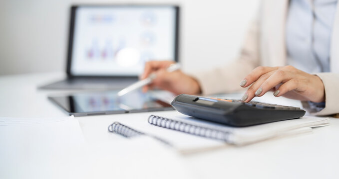 Businesswoman using calculator and tablet for financial audit and data analysis in banner ratio