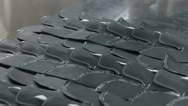 Stacked leather shoe uppers arranged on a worktable in a footwear factory setting