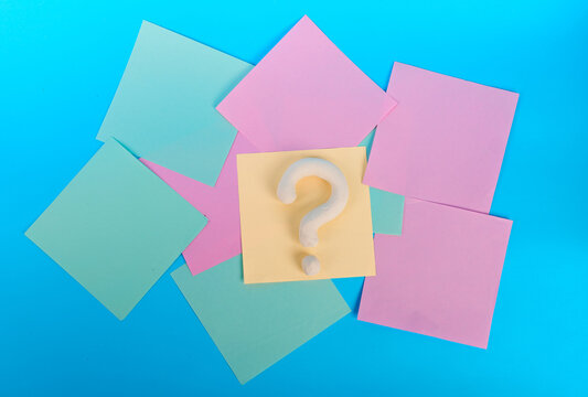 White question mark on central yellow note surrounded by colorful pastel notes on blue background
