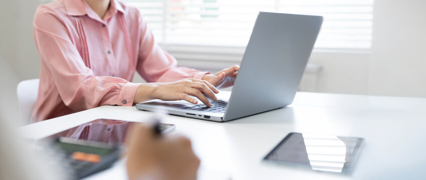 Businesswoman working on laptop computer at office desk in banner size