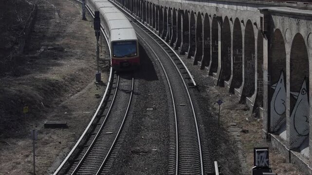An elevated view shows a S-Bahn train traveling along railway tracks in an urban setting.