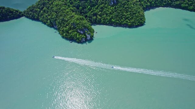 Cinematic drone tracking shot following speedboats across emerald tropical waters before revealing the hidden Dayang Bunting Lake, one of Langkawi's most spectacular natural landmarks.
