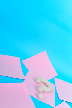 White 3D question mark among scattered pink notes on bright blue background
