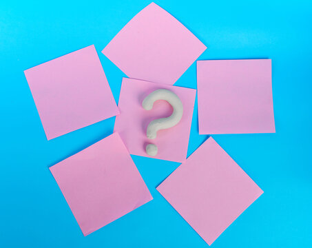 White question mark centered among blank pink notes on bright blue background
