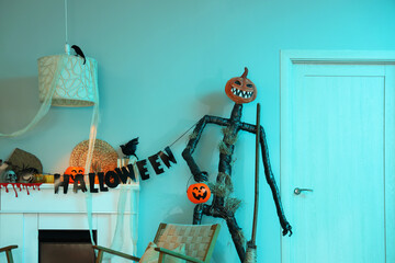 Obraz premium Interior of festive living room with armchair, garland, Spooky Halloween monster and autumn decorations on fireplace