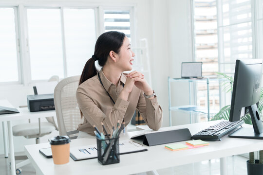 Young Businesswoman Working at Office Desk While Managing Documents and Mobile Communication.