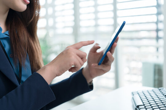 Young Businesswoman Working at Office Desk While Managing Documents and Mobile Communication.
