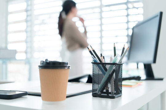 Young Businesswoman Working at Office Desk While Managing Documents and Mobile Communication.