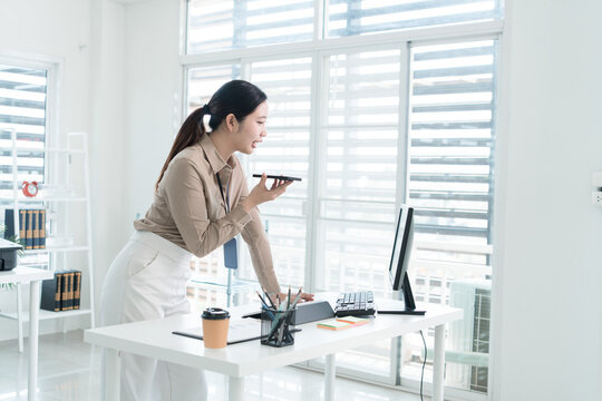 Young Businesswoman Working at Office Desk While Managing Documents and Mobile Communication.