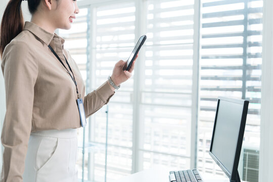Young Businesswoman Working at Office Desk While Managing Documents and Mobile Communication.