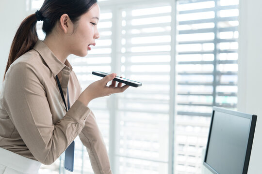 Young Businesswoman Working at Office Desk While Managing Documents and Mobile Communication.