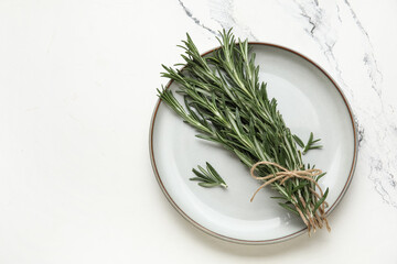 Fototapeta premium Plate with bunch of fresh rosemary on marble background