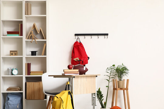 Interior of light classroom with desk, backpacks and shelf unit