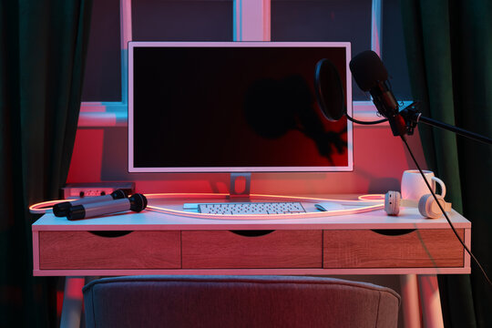 Workplace with computer and microphones in dark recording studio